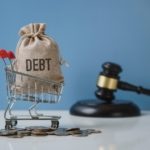 Debt. Money bag and shopping trolley with the hammer of the judge. Concept of financial crisis.